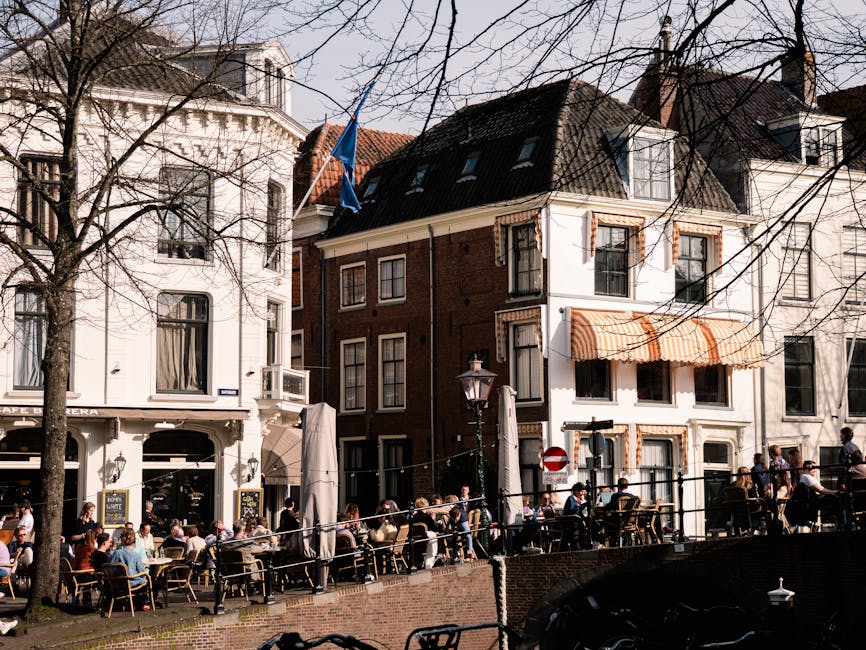 Een druk terrasje in Leiden, waar mensen genieten van het zonnige weer aan de gracht.